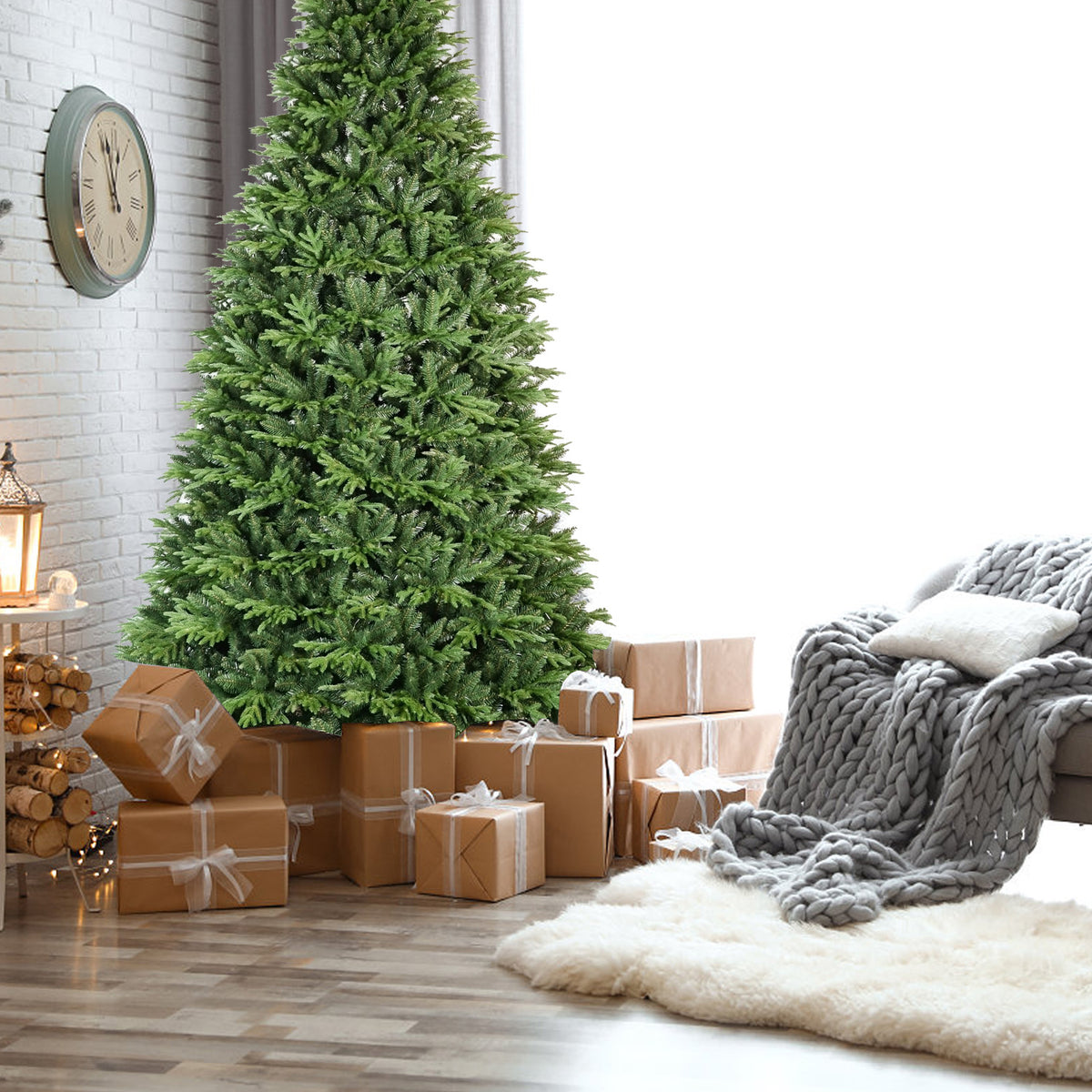 Full green PE/PVC artificial Christmas tree displayed indoors beside a sofa and holiday gifts